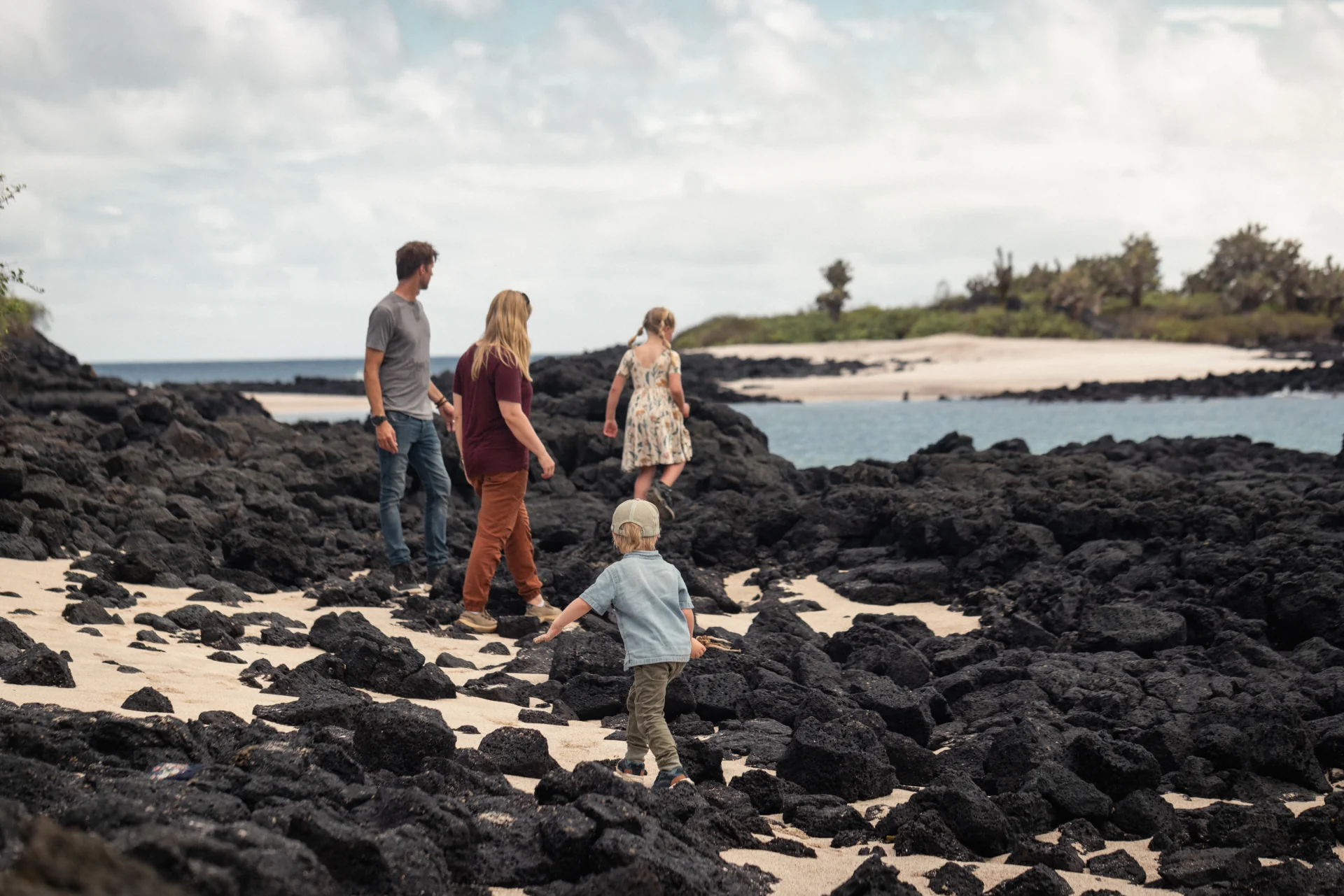 Multi-generational family exploring volcanic rocks on a Galapagos beach at golden hour