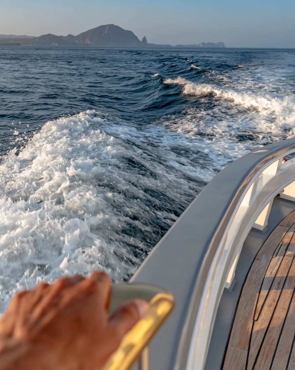 A small catamaran and a large monohull side by side in heavy open-water swell, showing the difference in pitch motion.